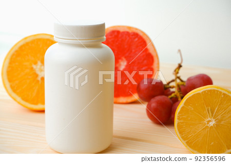 Vitamins. White empty bottle for vitamins on a background of citrus fruit slices. lemon. orange. White background. Blank Medicine bottle 92356596
