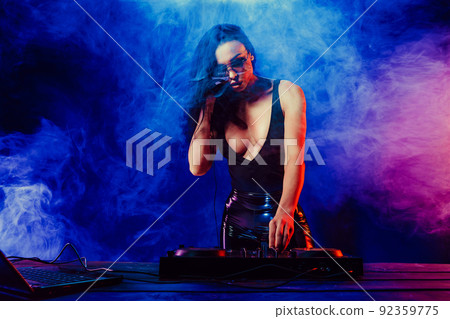 Sexy beautiful woman posing in headphones against abstract blue red background with smoke Sexy beautiful woman posing in headphones against abstract blue red background with smoke 92359775