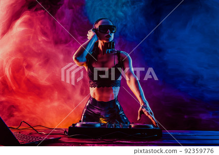 Sexy beautiful woman posing in headphones against abstract blue red background with smoke Sexy beautiful woman posing in headphones against abstract blue red background with smoke 92359776