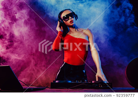 Sexy beautiful woman posing in headphones against abstract blue red background with smoke Sexy beautiful woman posing in headphones against abstract blue red background with smoke 92359777