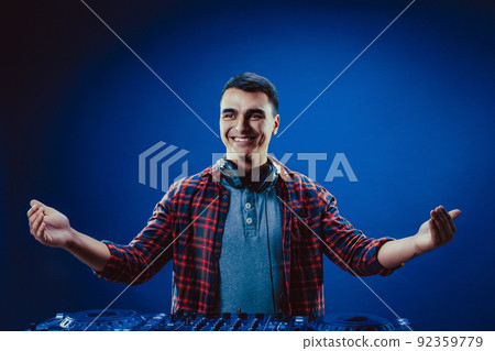 exicted dj sound device oprator with headphones by dancing at club - concept of entertainment, nightlife, music club and musician 92359779