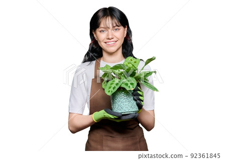 Smiling young woman in apron gloves with potted plant on white isolated background 92361845