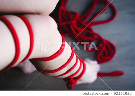 Female legs are tied with red rope. Female legs are tied with red rope. 92361923
