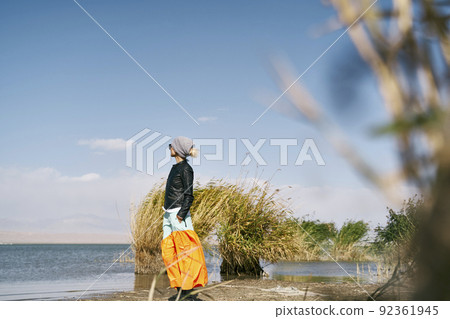 asian woman tourist standing by a lake looking at view under blue sky 92361945