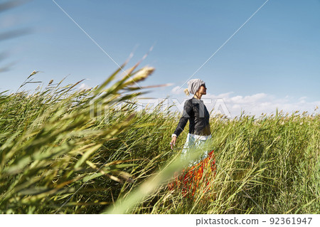 asian woman enjoying fresh air and sunlight in a field of reeds 92361947