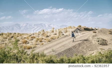 rear view of an asian man backpacker photographer walking on a dirt road through gobi desert rear view of an asian man backpacker photographer walking on a dirt road through gobi desert 92361957