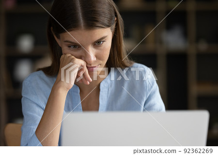 Close up face tired unmotivated female, staring at laptop screen Close up face tired unmotivated female, staring at laptop screen 92362269