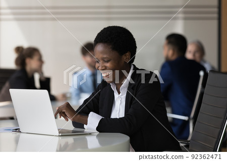 Cheerful happy millennial African businesswoman working at laptop Cheerful happy millennial African businesswoman working at laptop 92362471