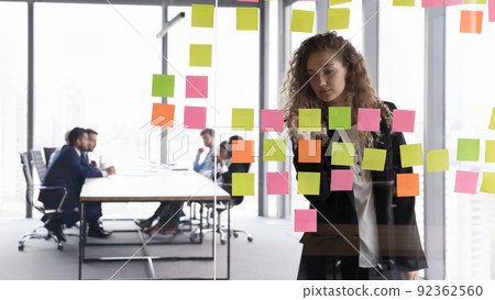 Busy focused businesswoman writing memos on paper notes 92362560