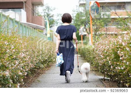 一個女人帶著她的狗沿著長廊散步 一個女人帶著她的狗沿著長廊散步 92369063