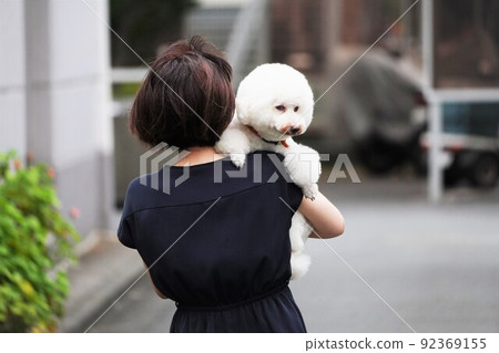 一個女人抱著一隻厭倦了走路的寵物狗 92369155
