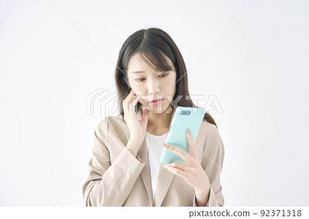 Business woman worried about looking at her smartphone White background 92371318