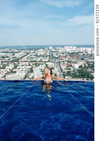 Woman in swimming pool on roof Woman in swimming pool on roof 92371539