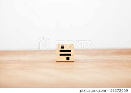 幾乎相等的符號。 ≒。不相等。寫在木塊上。黑色字母。木桌背景。 92372909