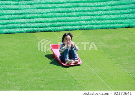 Girl enjoying grass sliding 92373641