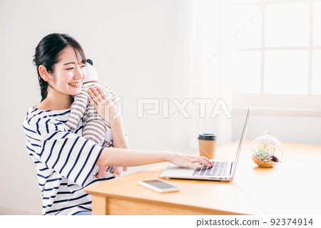 在家抱著嬰兒遠程工作的女性(育兒/看護) 在家抱著嬰兒遠程工作的女性(育兒/看護) 92374914