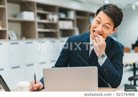 A man biting his nails at work 92376466