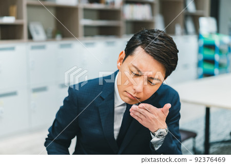 A man who smells the palm of his hand at work A man who smells the palm of his hand at work 92376469