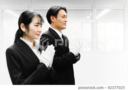 Men and women in suits wearing white gloves and holding hands (funeral director / funeral) Men and women in suits wearing white gloves and holding hands (funeral director / funeral) 92377025