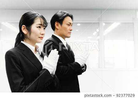 Men and women in suits wearing white gloves and holding hands (funeral director / funeral) 92377029