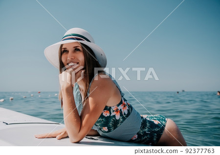 SUP Stand up paddle board. Young woman sailing on beautiful calm sea with crystal clear water. The concept of an summer holidays vacation travel, relax, active and healthy life in harmony with nature. 92377763