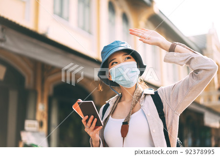 Walking young adult asian woman traveller wear face mask for covid-19 traveling in city on summer 92378995