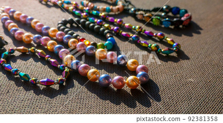 Heap of colored bright jewelry beads on a dark background. Different gems beads necklace. Jewel necklace modern fashion pattern or texture. jewellery background Heap of colored bright jewelry beads on a dark background. Different gems beads necklace. Jewel necklace modern fashion pattern or texture. jewellery background 92381358