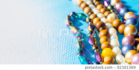 Heap of colored bright jewelry beads on a blue background. Different gems beads necklace. Jewel necklace modern fashion pattern or texture. copy space. Heap of colored bright jewelry beads on a blue background. Different gems beads necklace. Jewel necklace modern fashion pattern or texture. copy space. 92381369