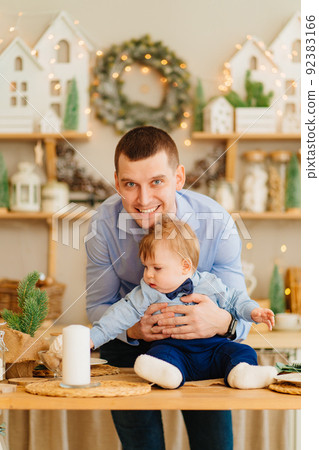 dad and baby son in the decorated for the new year kitchen. father's day dad and baby son in the decorated for the new year kitchen. father's day 92383166