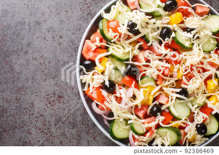 Traditional Shopska salad with vegetables, olives and cheese close-up in a plate. Horizontal top view 92386469