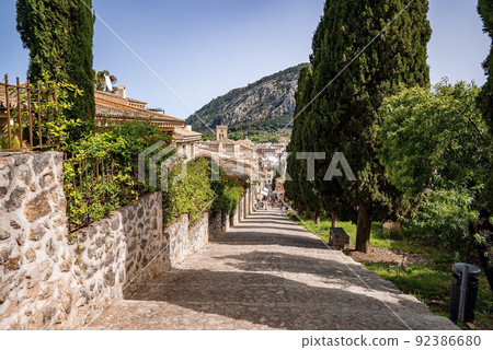 Pathway amidst trees and houses in old town against mountain during summer Pathway amidst trees and houses in old town against mountain during summer 92386680