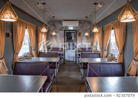 Seats and tables arranged in illuminated train coach at famous Peatus in town Seats and tables arranged in illuminated train coach at famous Peatus in town 92387079