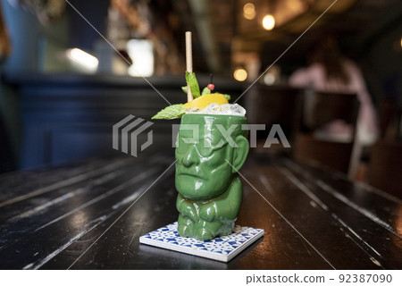 Close-up of cocktail in figurine shape glass on coaster at table in restaurant 92387090