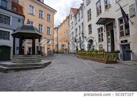 Tourists sitting at Cat's well on Rataskaevu Street amidst buildings in old town Tourists sitting at Cat's well on Rataskaevu Street amidst buildings in old town 92387107