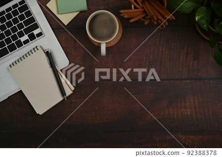 Top view laptop computer, notepad, sticky notes and coffee cup on wooden background with copy space Top view laptop computer, notepad, sticky notes and coffee cup on wooden background with copy space 92388378