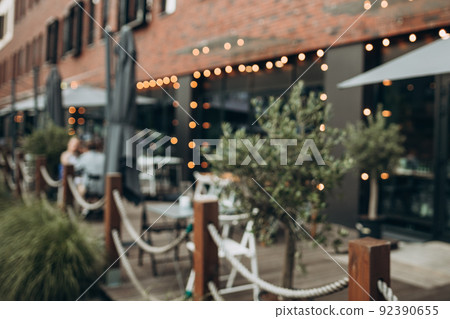 Blurred background of outdoor restaurant with abstract bokeh light. Outdoor cafe with tables and chairs Blurred background of outdoor restaurant with abstract bokeh light. Outdoor cafe with tables and chairs 92390655