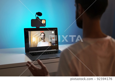 A young blogger records a video with himself on his phone in his studio. A young blogger records a video with himself on his phone in his studio. 92394176