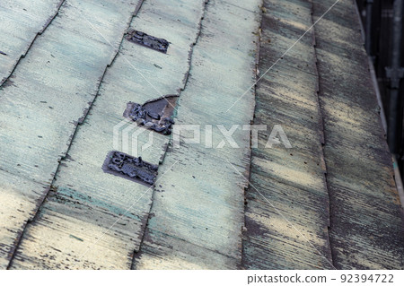 A 25-year-old single-family house with a faded and dirty roof that requires maintenance 92394722