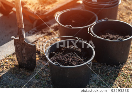 closeup of garden bucket with black soil and shovel in ground for planting tree 92395288