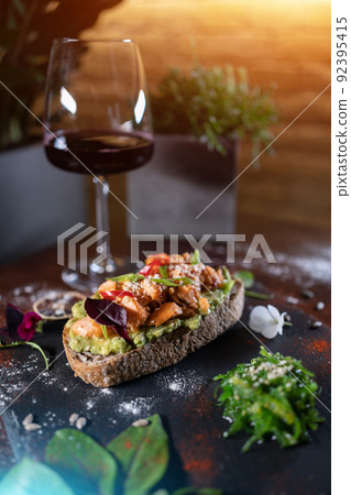 wine glass and fresh sandwich with avocado, red salmon fried fish, seaweed wine glass and fresh sandwich with avocado, red salmon fried fish, seaweed 92395415