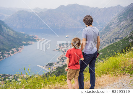 Father and son travellers enjoys the view of Kotor. Montenegro. Bay of Kotor, Gulf of Kotor, Boka Kotorska and walled old city. Travel to Montenegro concept. Fortifications of Kotor is on UNESCO World 92395559