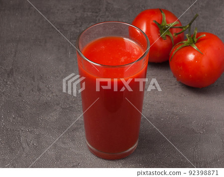 tomato juice in a glass decorated with tomatoes on a gray background tomato juice in a glass decorated with tomatoes on a gray background 92398871