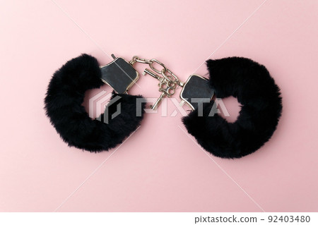 Black fluffy handcuffs. Erotic sex game with sexual bdsm toy. Pink background Black fluffy handcuffs. Erotic sex game with sexual bdsm toy. Pink background 92403480