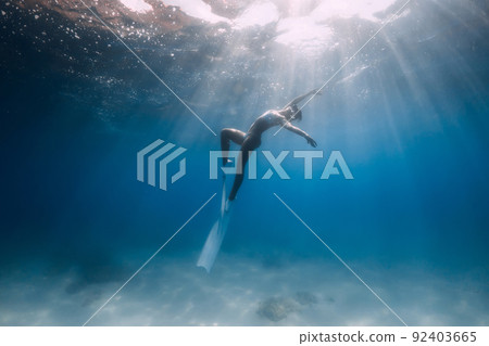 Freediver with white fins. Attractive woman posing underwater in blue sea 92403665