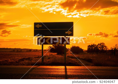 Empty blue direction crossroads road signs representing oportunities with red burning sunset background. Choose your strategy. Copyspace. 92404047