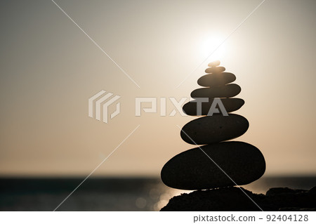 Balanced rock pyramid on the pebble beach on sunset. Selective focus Abstract bokeh with Sea on the background. Zen stones on the sea beach, meditation, spa, harmony, calmness, balance concept Balanced rock pyramid on the pebble beach on sunset. Selective focus Abstract bokeh with Sea on the background. Zen stones on the sea beach, meditation, spa, harmony, calmness, balance concept 92404128