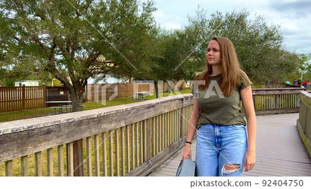 Young woman walks across a jetty in the Everglades Young woman walks across a jetty in the Everglades 92404750