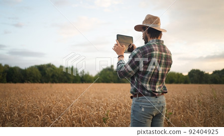 Farmer working with tablet computer on wheat field Farmer working with tablet computer on wheat field 92404925