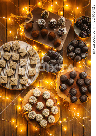 Assorted chocolates on wooden table with garland 92406423