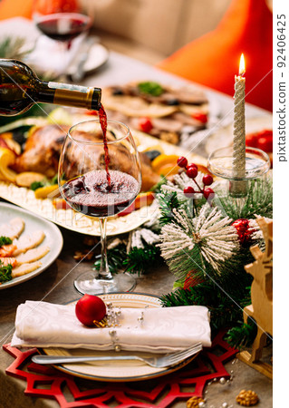 Pouring red wine in a glass on new year table Pouring red wine in a glass on new year table 92406425
